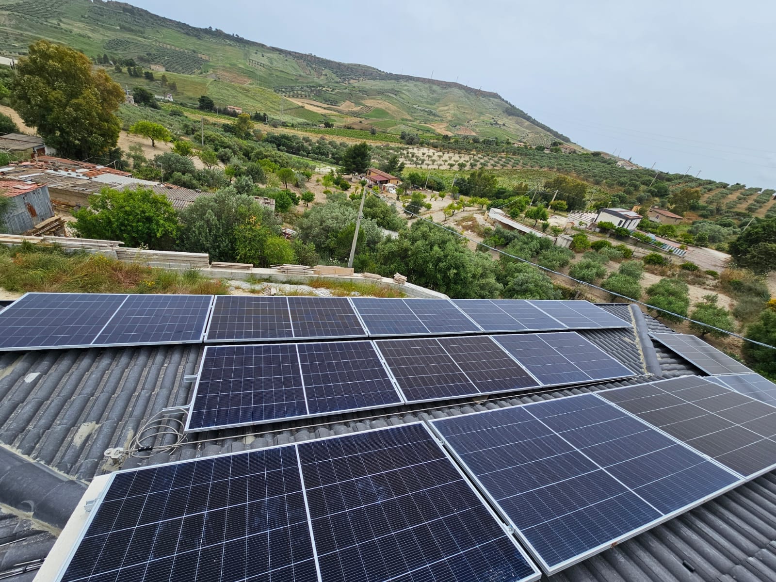 Impianto fotovoltaico realizzato da Carusotto Impianti sulla copertura di un edificio, con le campagne di Canicattì sullo sfondo